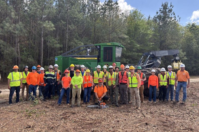 ProLogger logger safety training participants in hard hats and safety vests at a logging site
